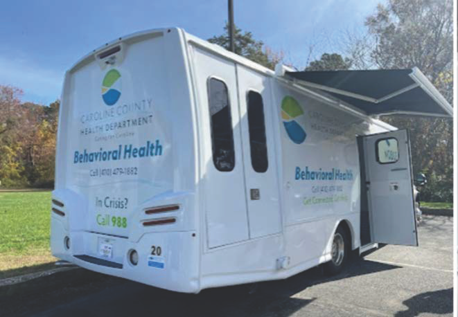 Back of a mobile van with two doors to enter and sign on side that reads Caroline County Health Department Behavioral Health and a phone number
