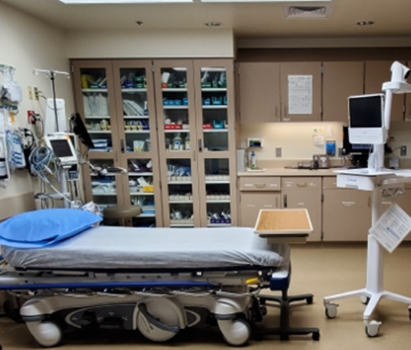 Room in an emergency department with a telehealth cart facing the bed.