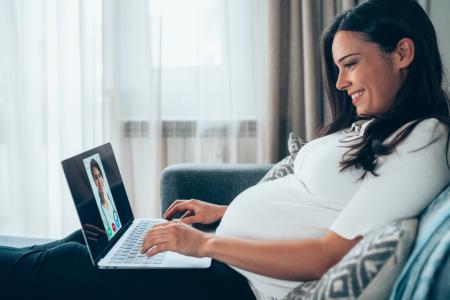 Pregnant woman talking with provider on laptop.